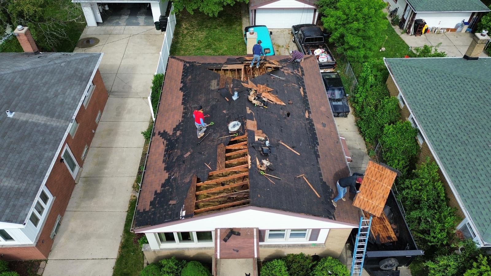 Aerial drone view of GSKI crew tearing off old residential roof — full tear-off in progress